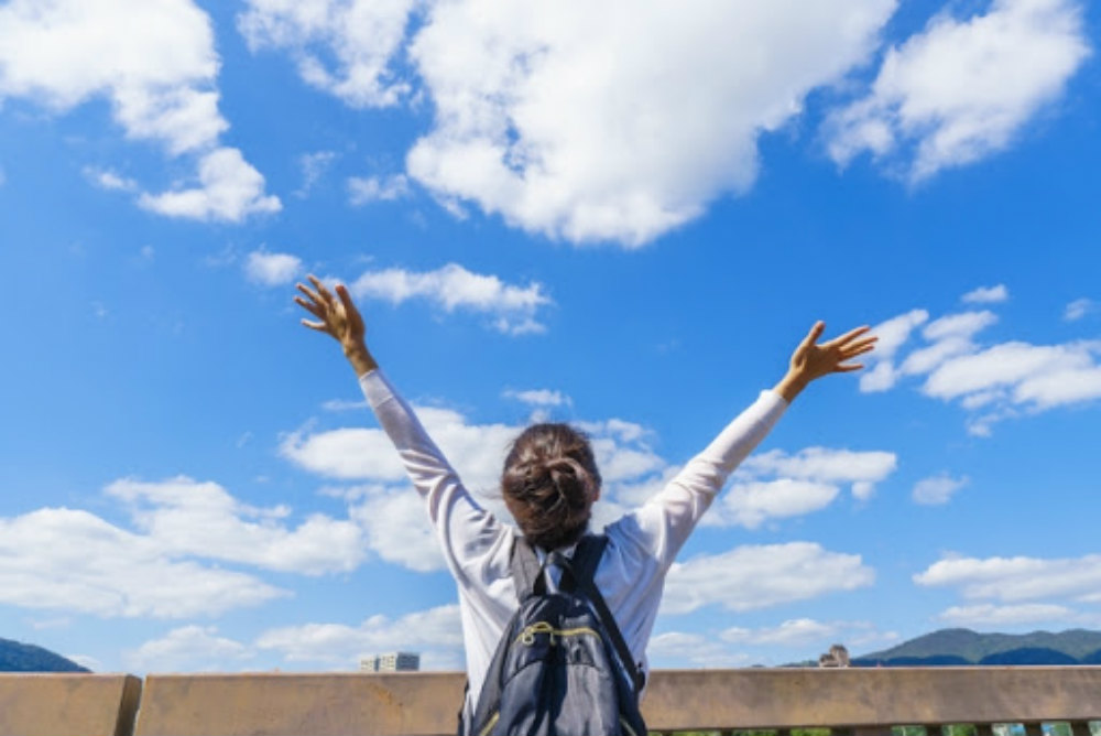 空に向かって手を挙げる女性